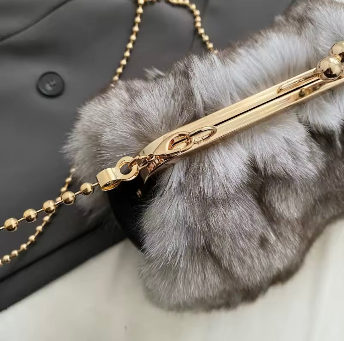 Gold chain with a fur pom-pom attached to a black coat.