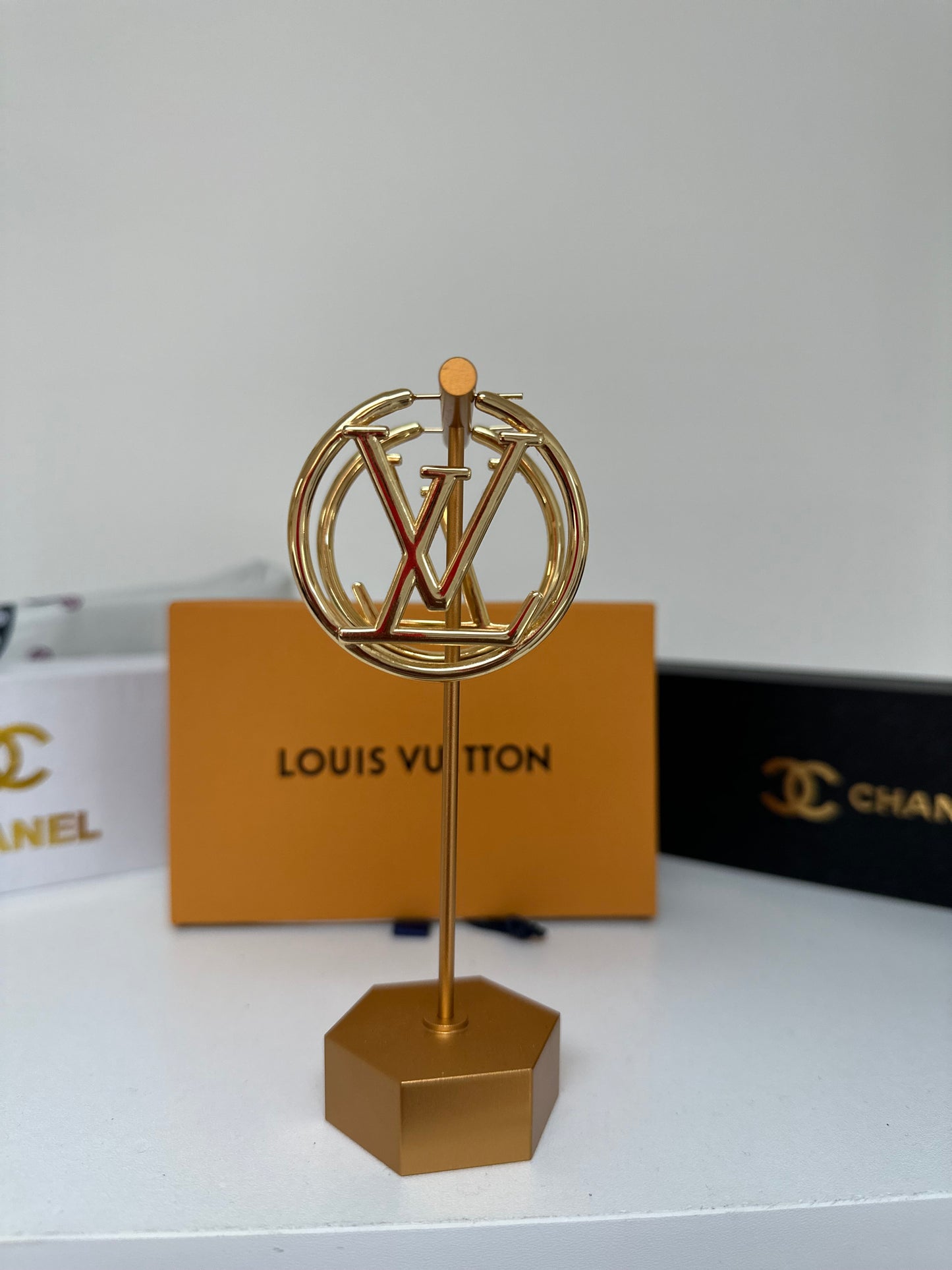 Gold earring on a stand with Louis Vuitton card in the background