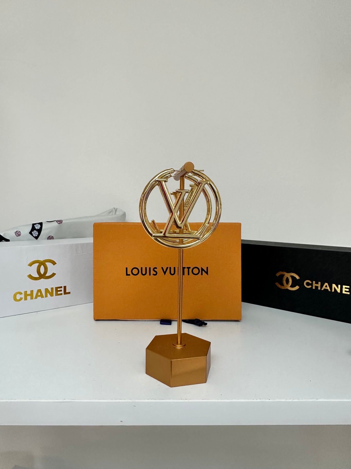 Gold earring on a Louis Vuitton earrings with Chanel branding in the background