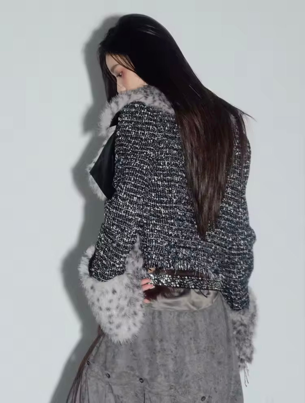 Person wearing a textured jacket with fur trim against a plain background