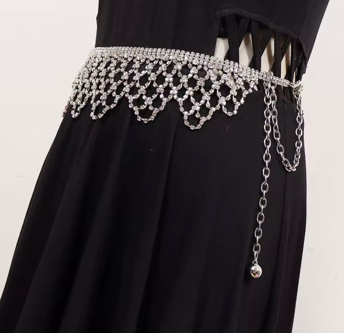 Black dress with a decorative silver belt on a plain background