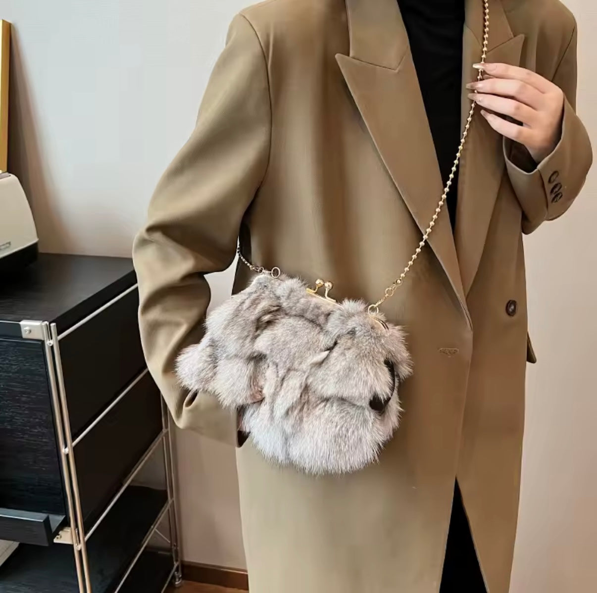 Person wearing a beige coat holding a fluffy gray handbag.